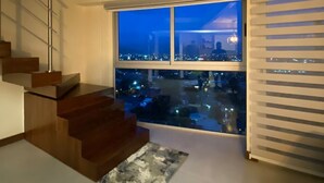 Un interior modernis amb una escala, una finestra gran amb vista a la ciutat i un sostre amb il·luminació empotrada.