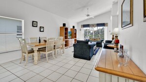 A spacious living area with a dining table, chairs, a sofa, and a TV stand. - In Orlando area, large Family Friendly Home - Close to Disney (Clermont)
