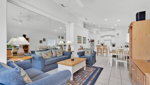 A spacious living room with a large sofa set, a coffee table, and a dining area with a white table and chairs. - In Orlando area, large Family Friendly Home - Close to Disney (Clermont)