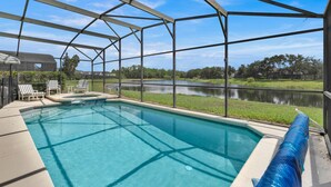 A swimming pool with a clear view of a lake, surrounded by a covered area with chairs and a view of the landscape. - In Orlando area, large Family Friendly Home - Close to Disney (Clermont)