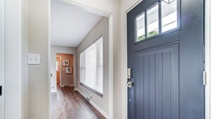 A hallway with a dark blue door, a light-colored wall, and a window with blinds. - Completely updated home! -Close to hospitals, UD, Wright Patt Air Force Base. (Kettering)