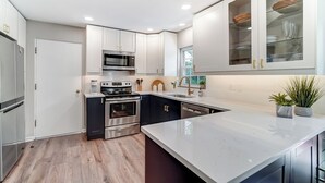 A modern kitchen with white cabinets, stainless steel appliances, and a large island. - Completely updated home! -Close to hospitals, UD, Wright Patt Air Force Base. (Kettering)