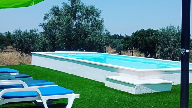 A swimming pool with blue lounge chairs and a green umbrella. - Monte Alentejano em Fronteira (Fronteira)