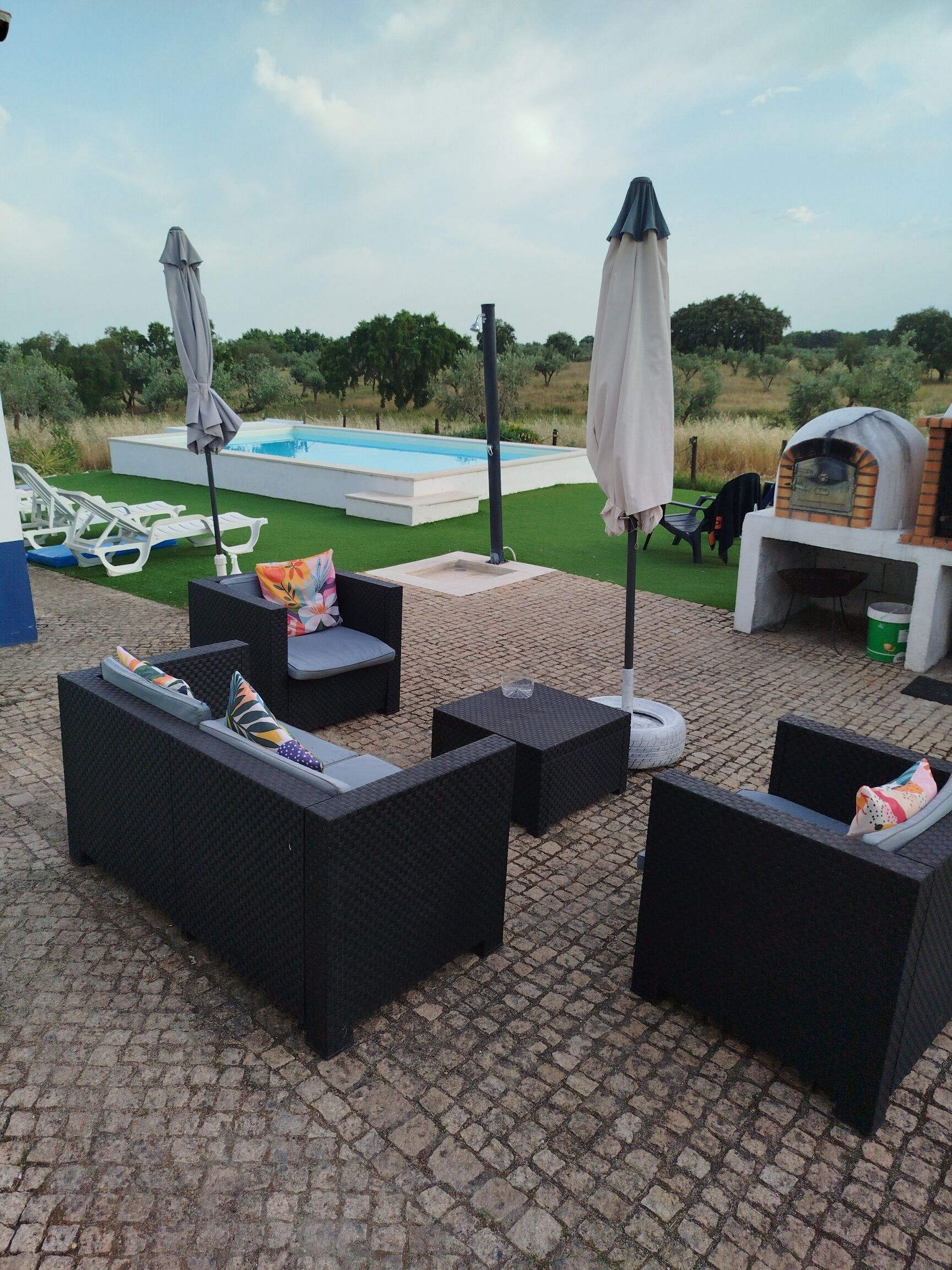 An outdoor patio with wicker furniture, a pool, and a barbecue area.