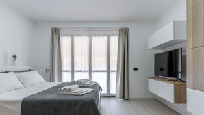 Una habitación de hotel moderna con una cama, un televisor y un mueble de madera empotrado.