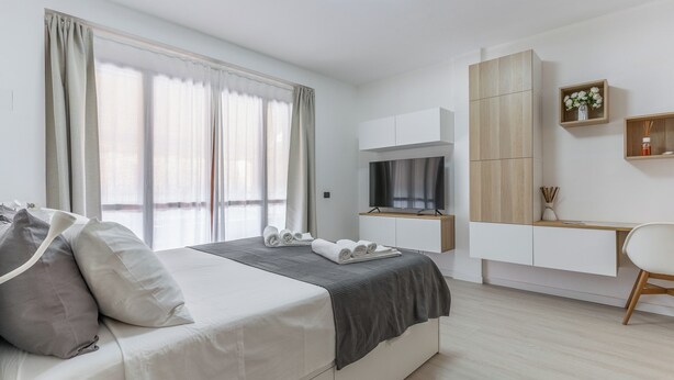 Una habitación de hotel moderna con cama, televisor, escritorio y armario.