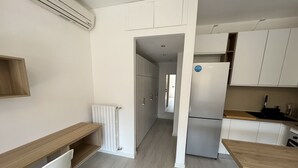 Una cocina moderna con armarios blancos, horno empotrado y refrigerador.