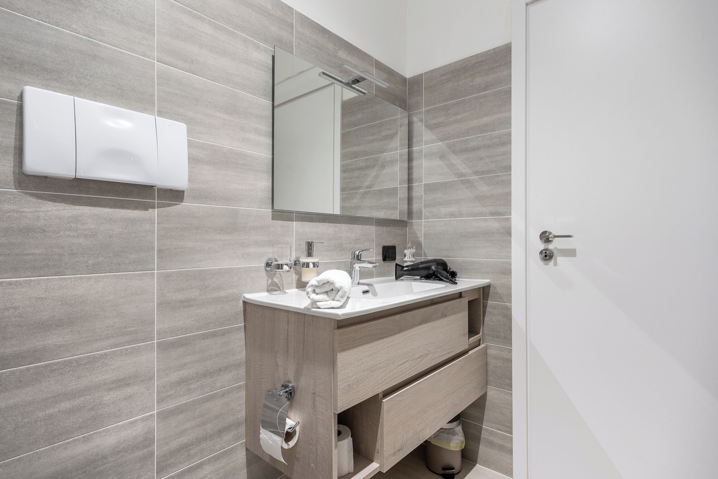 Une salle de bain moderne avec un meuble-lavabo en bois, un grand miroir et un lavabo blanc.