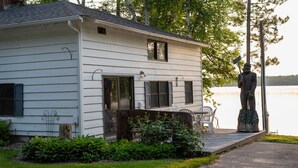 Une maison blanche avec des volets, un porche et une statue d’un homme tenant une canne à pêche.