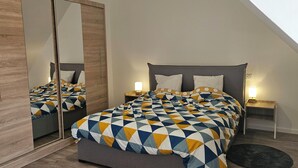 Ein Schlafzimmer mit einem Bett, Nachttischen, einem Spiegel und einem Kleiderschrank.