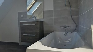 Ein modernes Badezimmer mit freistehender Badewanne, einem Waschtisch mit Spiegel und einem Oberlicht.