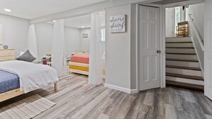 Ein Schlafzimmer mit Bett, Nachttisch, Kommode und einer Treppe, die in einen anderen Raum führt.