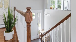 Eine Treppe mit weißen Geländern und einem hölzernen Handlauf, die zu einem Raum mit Fenster und Tür führt.