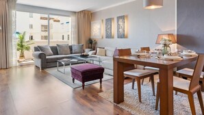 A modern living room with a sofa, coffee table, and dining table set up. - Apartment in Playas del Duque for 6 people| Casa Granada 146 (Puerto Banús - Marbella)