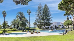 A resort with multiple swimming pools, lush greenery, and a clear view of the ocean. - Apartment in Playas del Duque for 6 people| Casa Granada 146 (Puerto Banús - Marbella)
