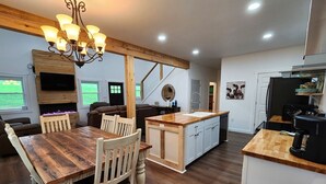 A modern kitchen with a wooden island, built-in appliances, and a dining area with a wooden table and chairs. - Quiet cabin 30 min from wineries, restaurants, Sugar Creek & Walnut Creek.  (Fresno)