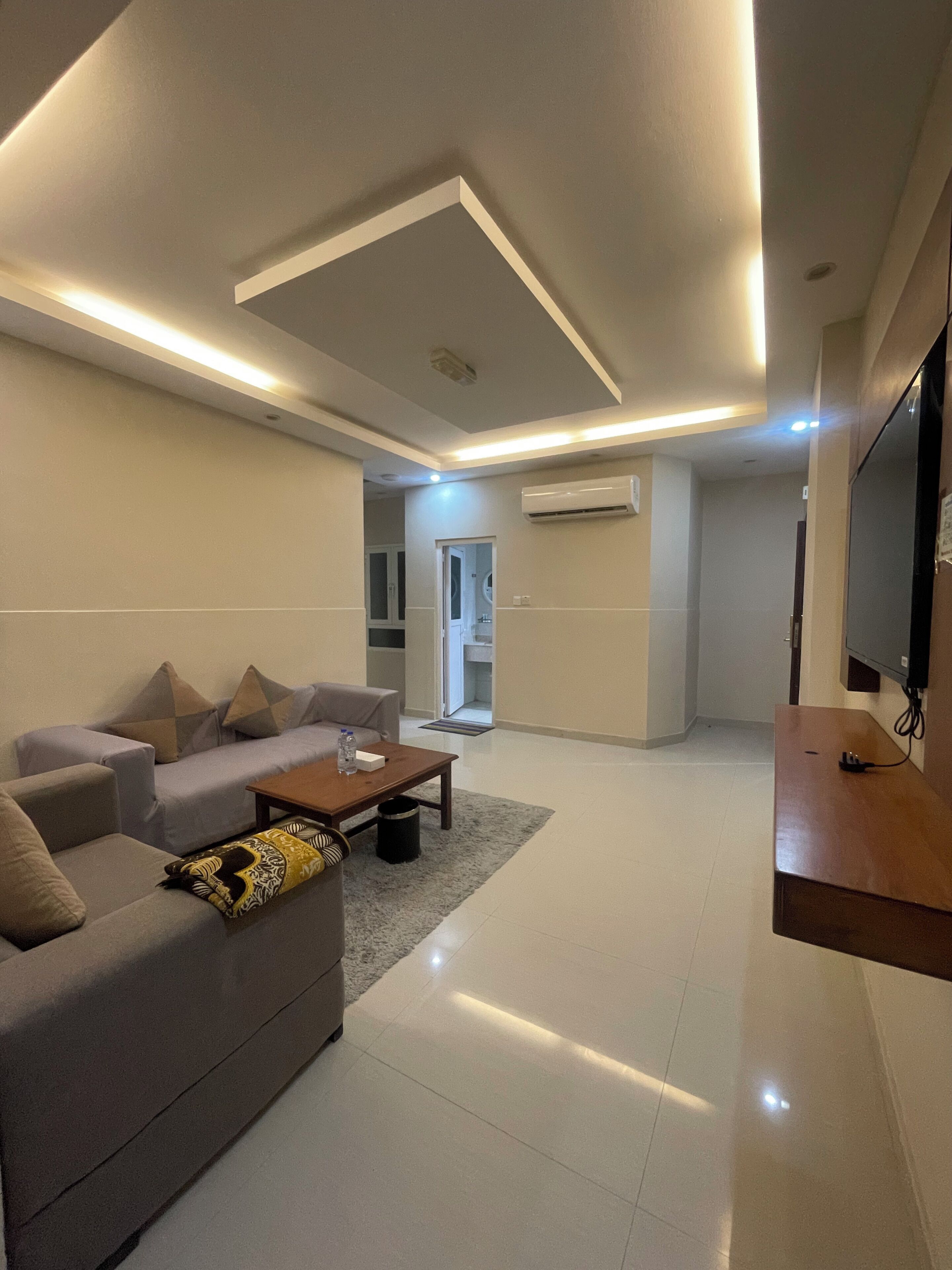 A modern living room with a sofa, coffee table, and a flat-screen TV.