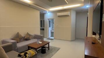 A modern living room with a sofa, coffee table, and a flat-screen TV.