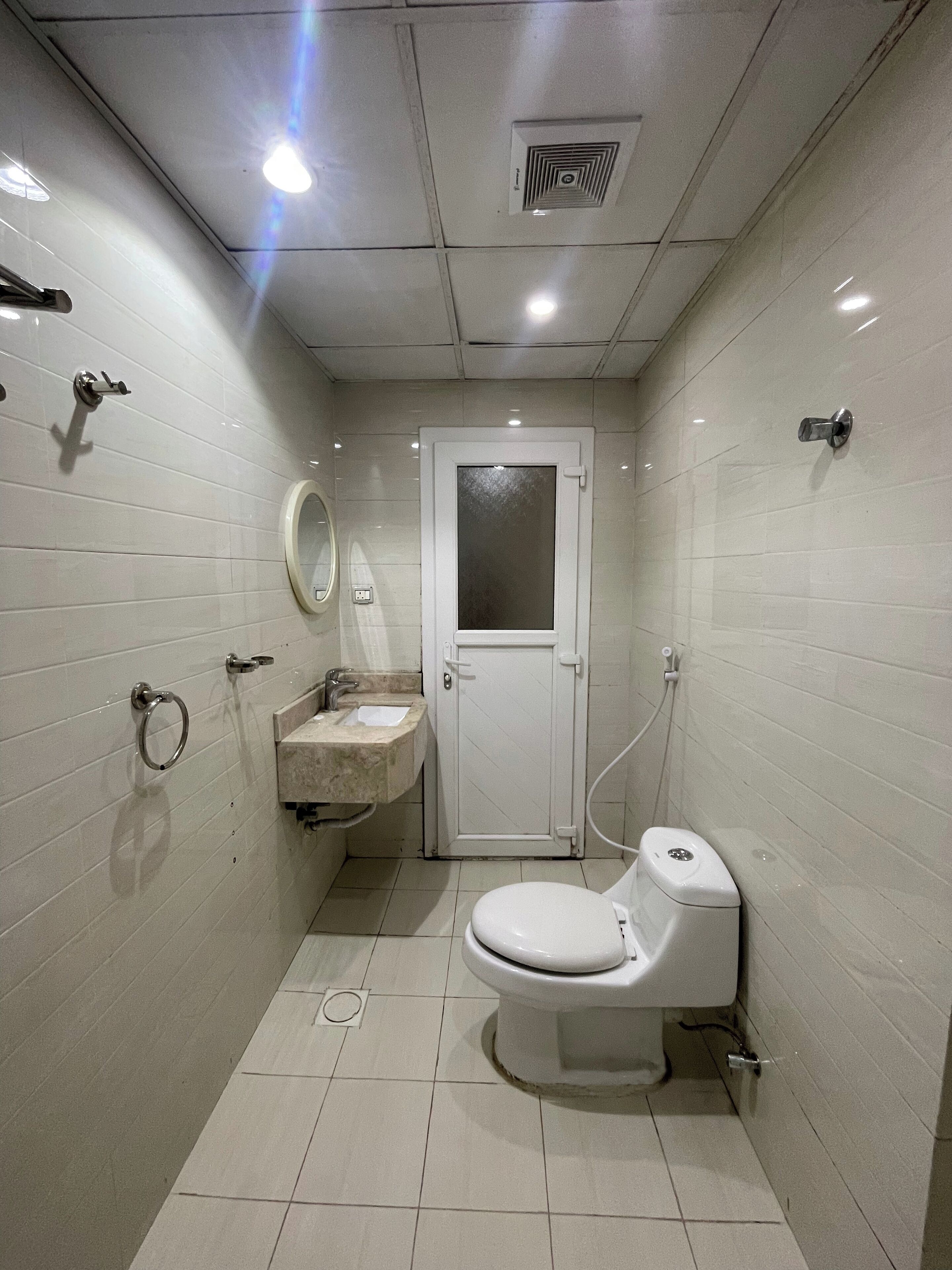 A small, compact bathroom with a toilet, sink, and mirror.