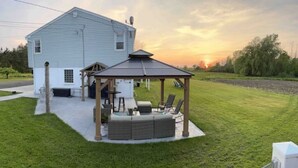 A house with a covered patio area featuring a seating arrangement and a small table. - Country Retreat One (North Tonawanda)
