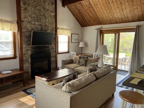 Enjoy a warm living area with a fireplace, comfortable seating, and a TV, offering a view of the outdoors.