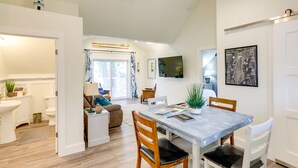 Eine moderne Küche mit Esstisch, Stühlen und einem an der Wand befestigten Fernseher.
