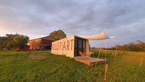 Una construcción rústica al aire libre con un gran letrero que dice "NULLE P.ART" y un pequeño espacio de descanso con sillas y una mesa.