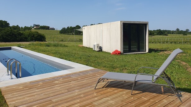 Una piscina con muelle de madera y una silla de descanso.