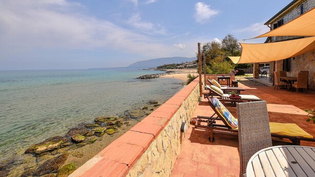 Un patio vista mare con posti a sedere all'aperto e un muro in pietra.