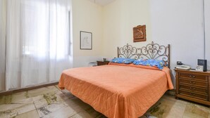 Una camera da letto con un letto, un comodino, una cassettiera e un quadro appeso al muro.
