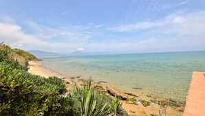 Una spiaggia costiera con acque cristalline, una riva sabbiosa e vegetazione verde.