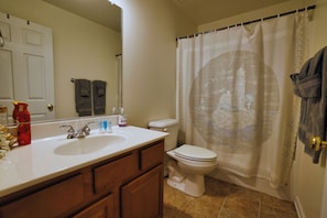 Un baño con un lavabo blanco, inodoro y cortina de ducha con diseño de castillo.