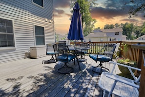 Une terrasse en bois avec une table et des chaises, un parasol bleu et une vue sur les maisons voisines.