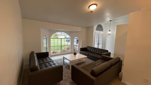 A spacious living room with a large window, a built-in bench, and a ceiling light. - Newly Updated House on Double Lot (North Port)