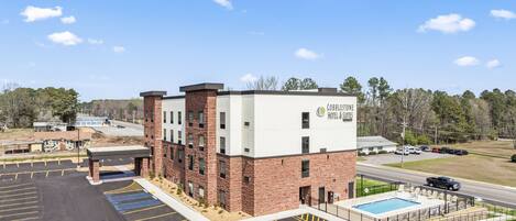 Un hôtel avec une façade en briques, une piscine et un parking.