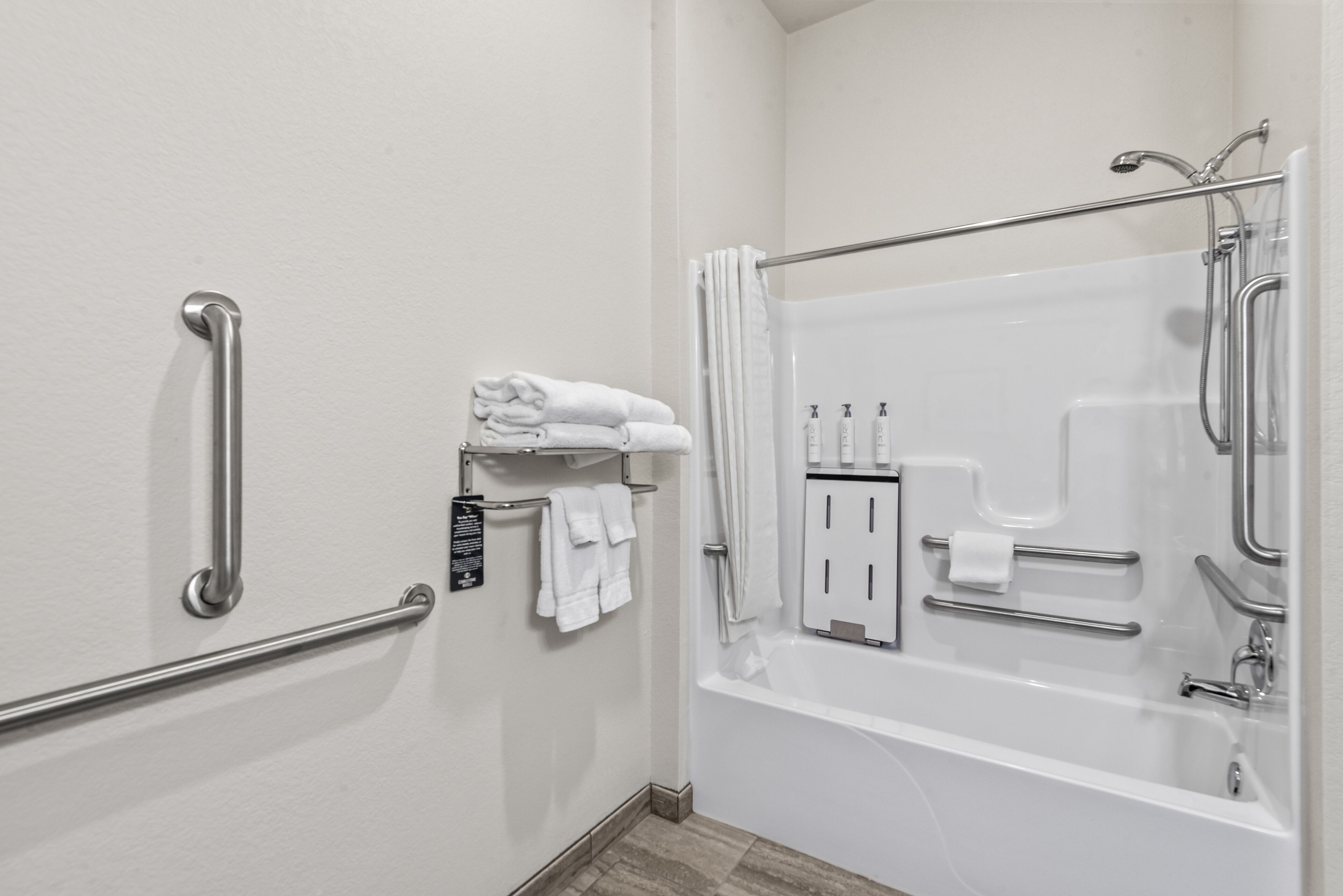 Une salle de bain équipée d’une baignoire, de barres d’appui, d’un porte-serviettes et d’un support à papier toilette.