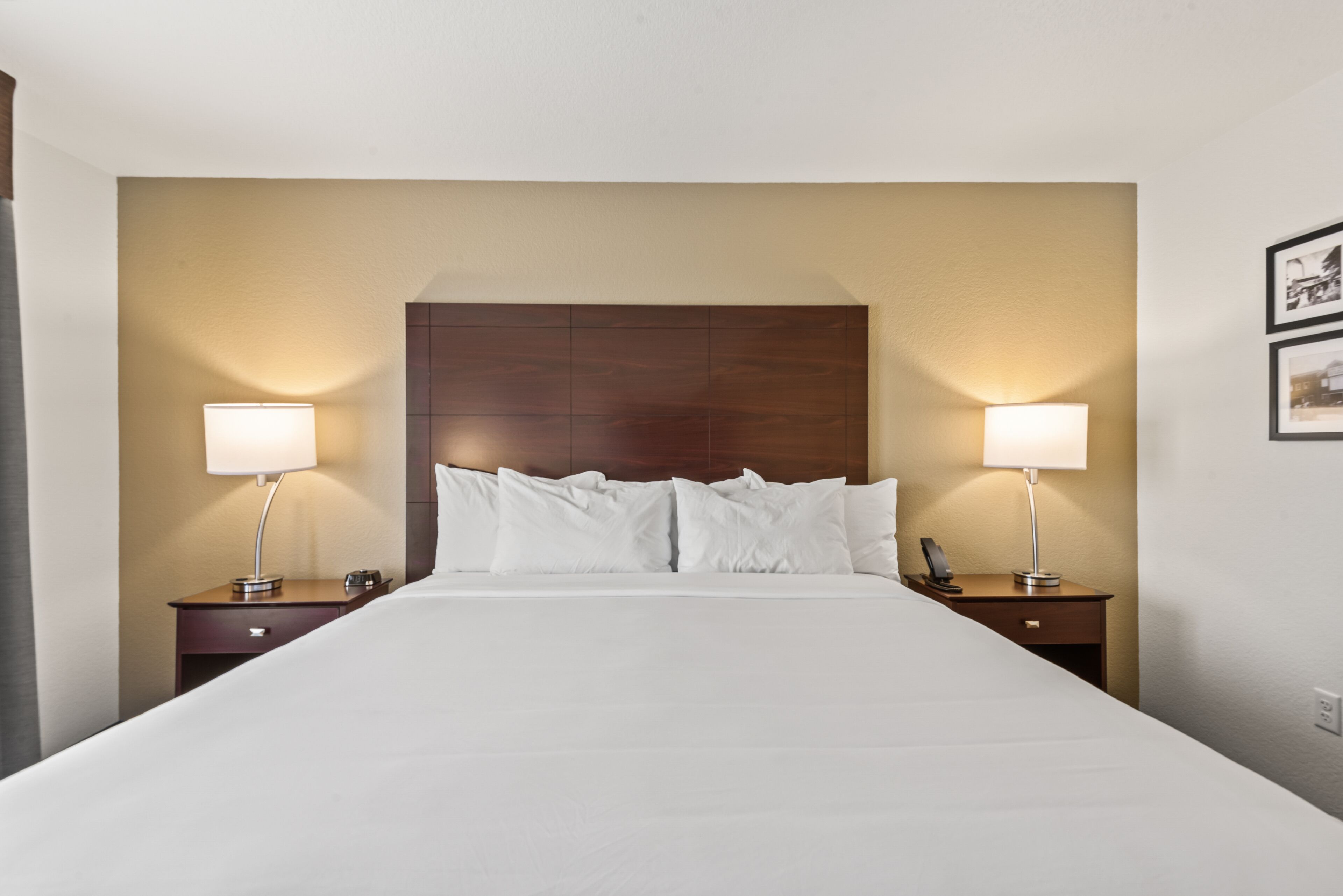 A hotel room with a large bed, two bedside tables with lamps, and a wooden headboard.