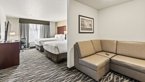 A hotel room with a large bed, a sofa, a desk, and a framed picture on the wall. - Cobblestone Hotel & Suites - Cullman (Cullman)