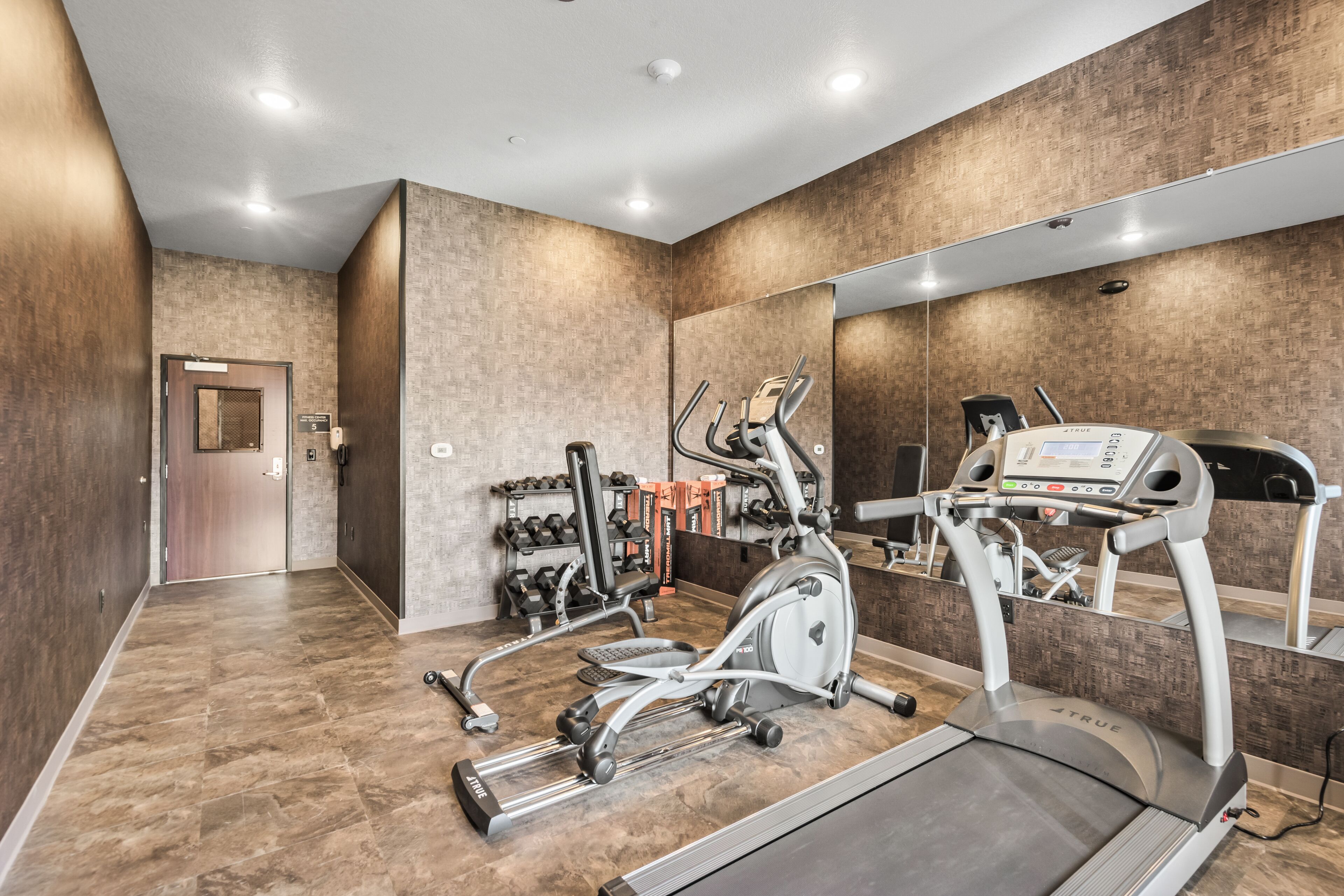 Een sportschool met loopband, crosstrainer en krachttoestellen.