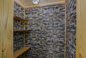 room with a stone wall and shelves for storage.
