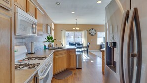 A kitchen with wooden cabinets, stainless steel appliances, and a dining area with a chandelier. - Pet-Friendly Needles Vacation Rental Near River! (Needles)
