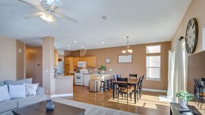 A spacious living room with a sofa, coffee table, and a dining area with chairs and a table. A kitchen with cabinets and appliances is visible in the background. - Pet-Friendly Needles Vacation Rental Near River! (Needles)