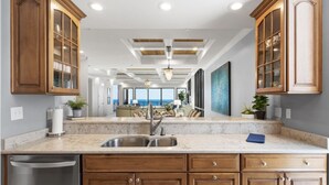 Cocina con armarios de madera, encimera de mármol y vistas al área de estar.