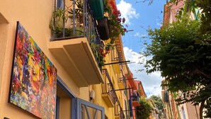 Eine enge Straße mit bunten Häusern, einer blauen Tür und gerahmten Kunstwerken an den Wänden.