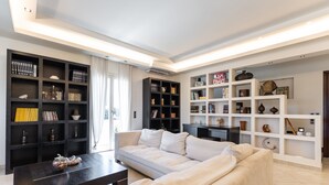 A modern living room with a beige sofa, dark wooden coffee table, and black and white shelving units filled with books and decorative items. - Villa with Private Pool & Jacuzzi Naxos (Naxos)