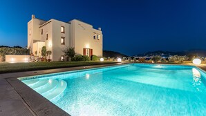 A modern building with a swimming pool, surrounded by well-maintained lawns and a view of distant hills. - Villa with Private Pool & Jacuzzi Naxos (Naxos)