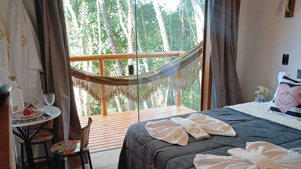 A room with a bed, a small table with chairs, and a hammock. - Pousada Vale do Horizonte (Camanducaia)