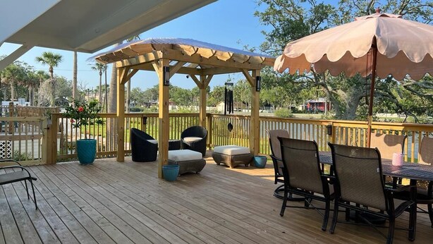 Une terrasse en bois, agréée de mobilier d’extérieur, notamment des chaises et une table, située sous une pergola dotée d’un auvent.