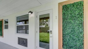 Eine Gebäudefassade mit weißer Außenwand, einer Tür mit Fensterglas und einer grünen Wandgestaltung.