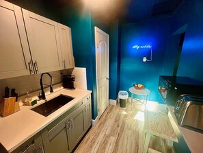 A compact kitchen with white cabinets, a black sink, and a neon sign on the wall. - Moody Stoody-O Near Las Olas Beach & Holiday Park (Fort Lauderdale)